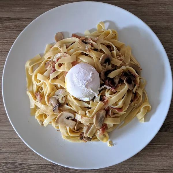 Tallarines salteados con champiñones y jamón con huevo escalfado